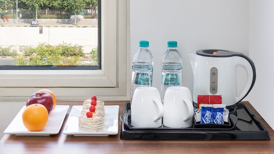 A bunch of amenities featuring water bottle, tea and coffee maker, and fruits at Inde Hotel Cyber City kept on a table