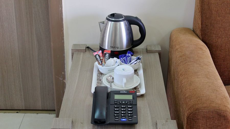 A picture of a kettle, coffee mugs, sachets and telephone on a table
