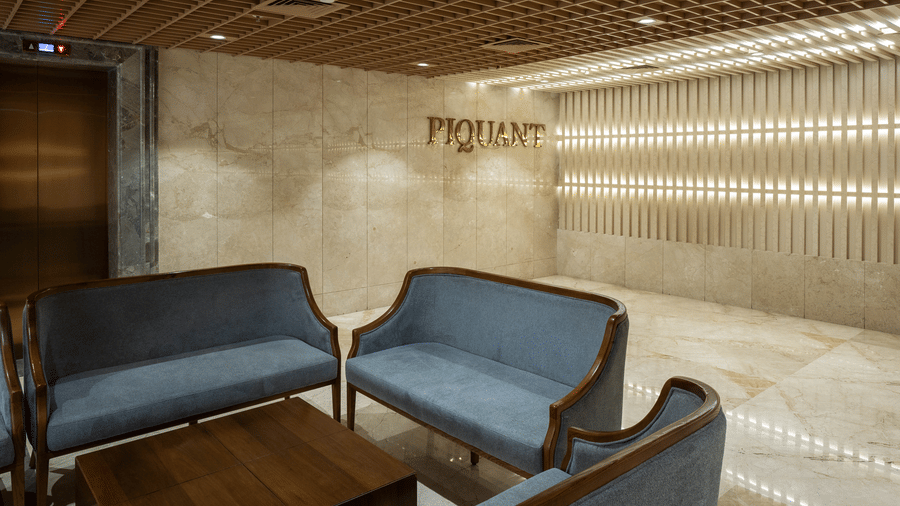 The contemporary lobby entrance of Piquante restaurant featuring plush blue sofas and soft ambient lighting - Praveg's Grand Eulogia, Ahmedabad