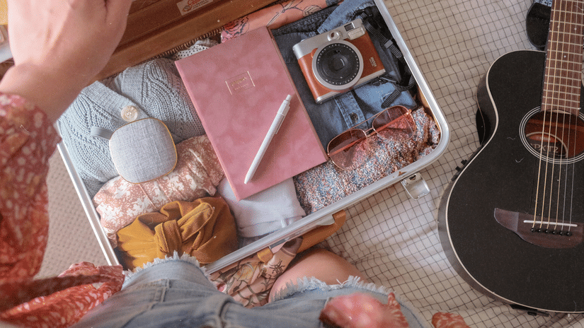 An overhead, slightly angled shot of a person packing their suitcase.