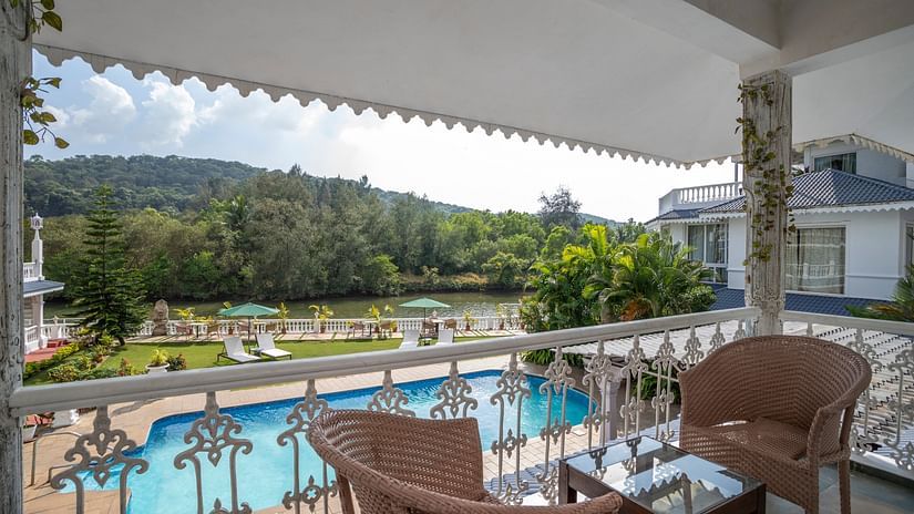 The Maharaj Balcony overlooks the pool and lush green hills - Stone Wood Riverfront Resort, Siolim