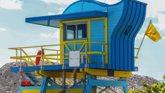 A life guards watch tower that is painted in blue and railings painted in yellow.