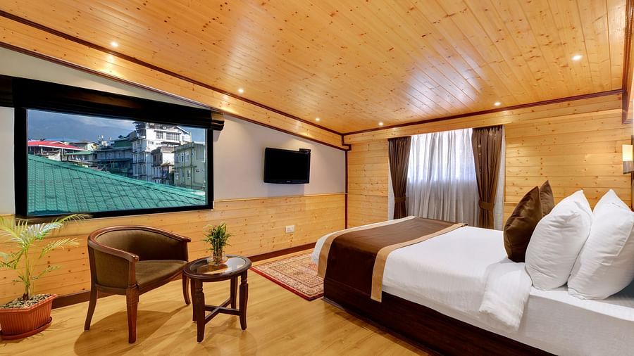 A queen bed opposite a sofa and table in attic family room - Sumitel Shangrila, Deorali