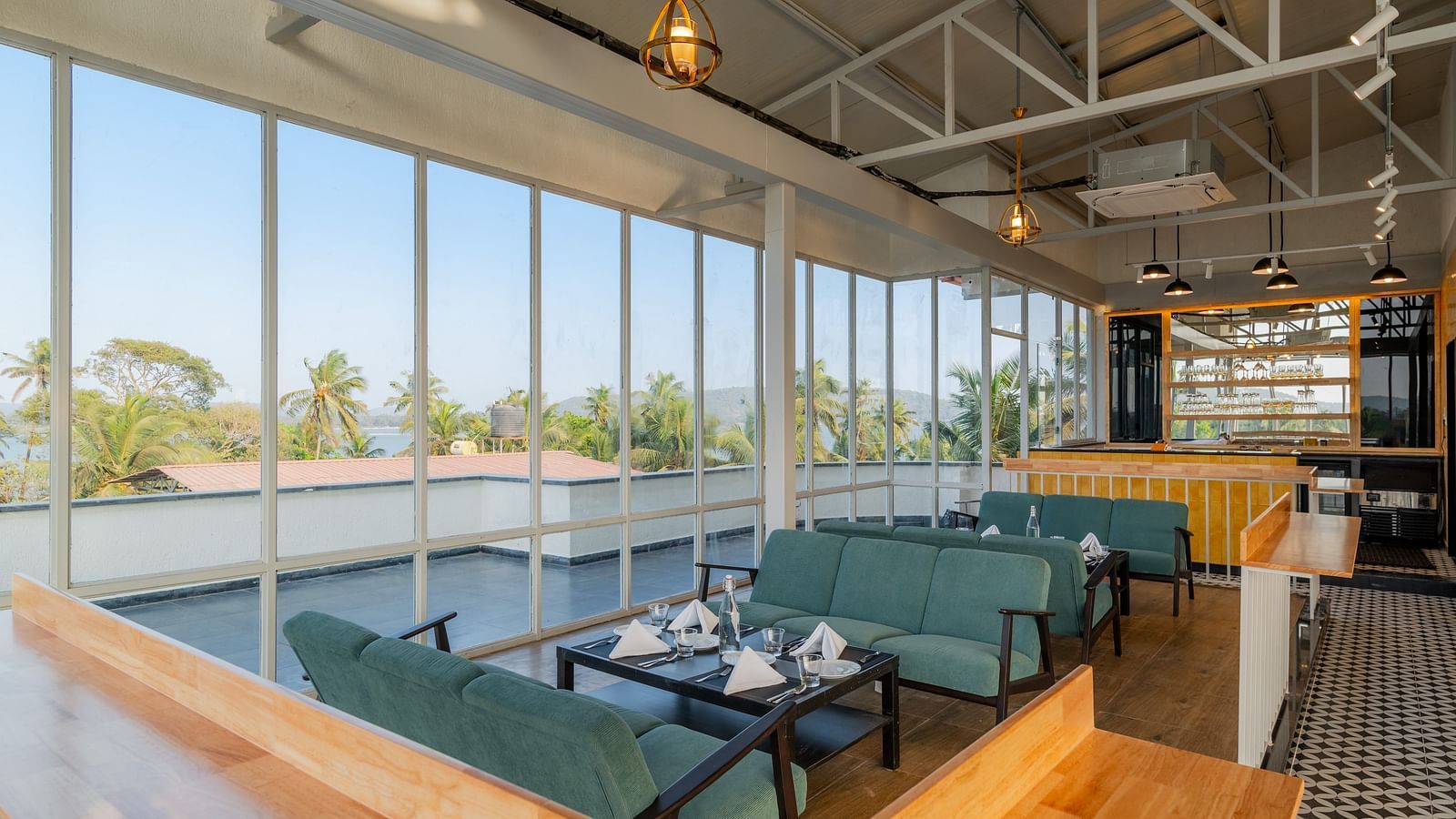 Spacious cafe interior with large windows and comfortable seating at Bedzzz Xclusiv Morjim, Goa