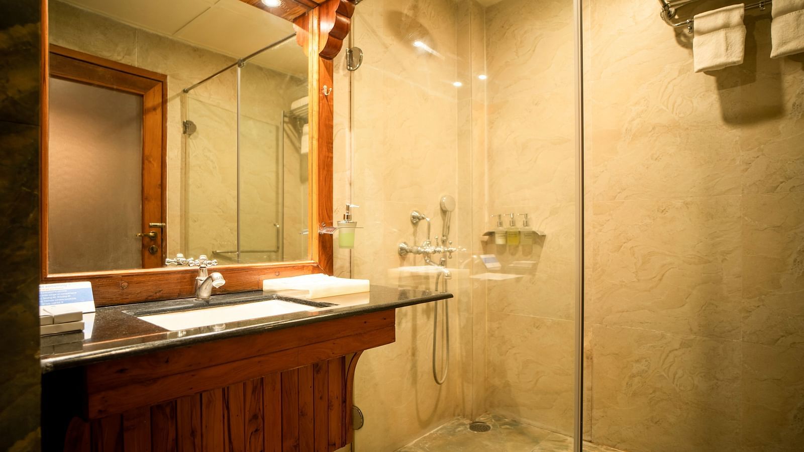 An image of a modern bathroom with a shower cubicle and a sink with a mirror placed in front of a sink - Coral Reef Resort & Spa, Havelock