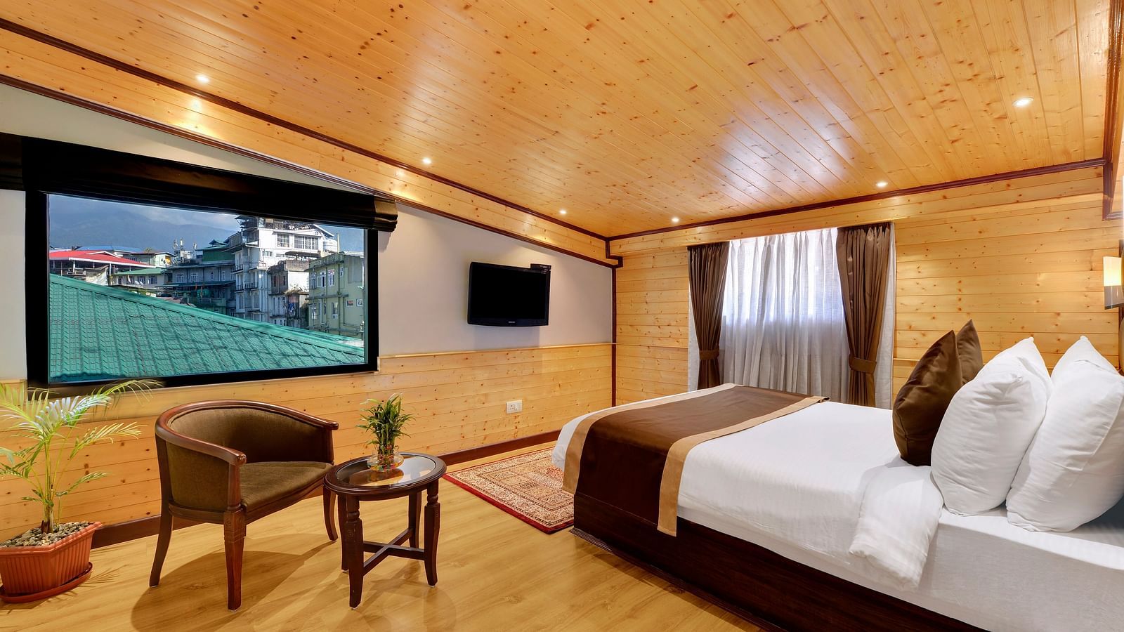A queen bed opposite a sofa and table in attic family room - Sumitel Shangrila, Deorali