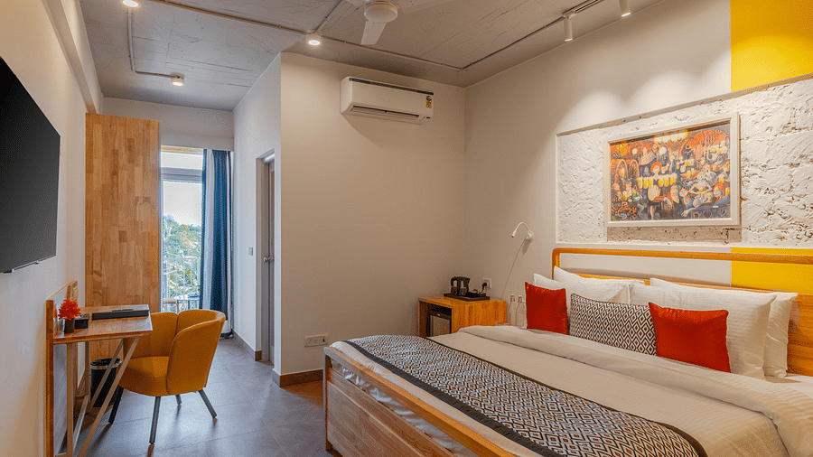 Bright hotel room with, flat TV screen, work desk and chair, vibrant art on the wall, and an access to the balcony at Bedzzz Xclusiv Morjim, Goa