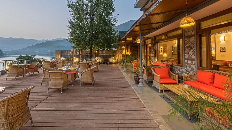 A side angle view of the Outdoor L-Attitude Deck at Fishermen's Lodge, Bhimtal, showcasing its inviting space and scenic surroundings.