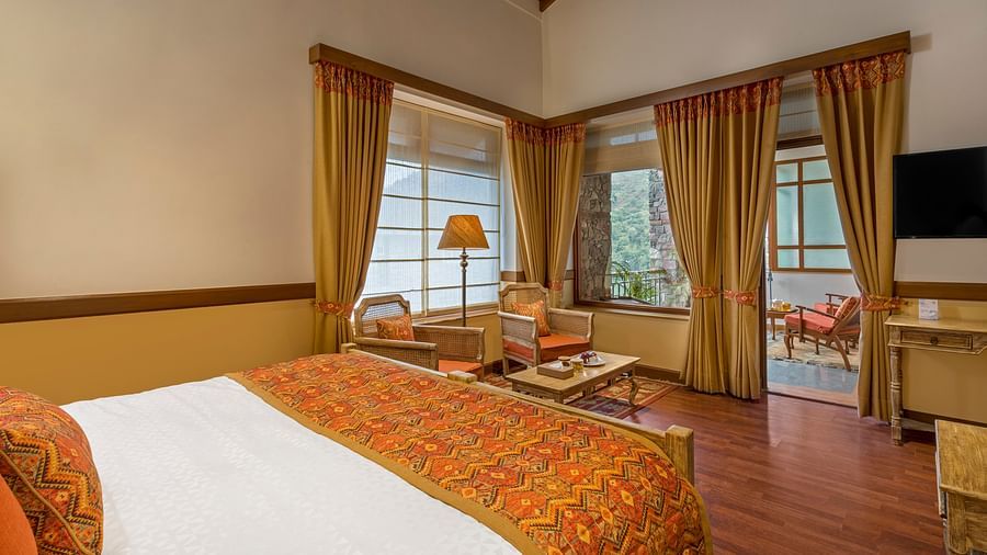 Top-side angle view of Superior Rooms at Fishermen's Lodge, Bhimtal, showcasing a plush bed, lamp stand, and flat-screen TV for a luxurious stay.