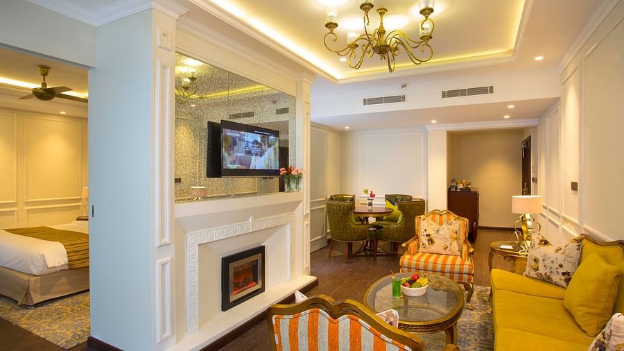 Suite living area with furniture around the table and a wall-mounted television above the fireplace
