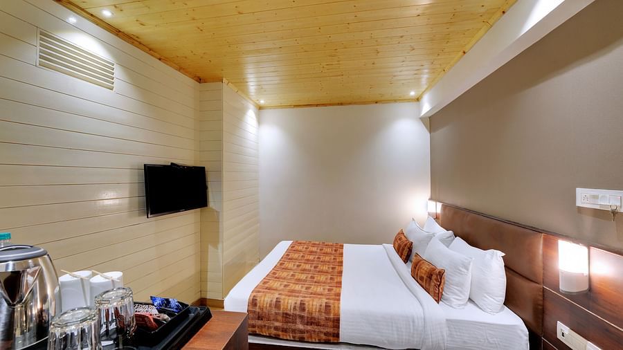 An image of a room with a queen size bed, TV and room amenities like tea coffee maker - Sumitel Vista TV Tower