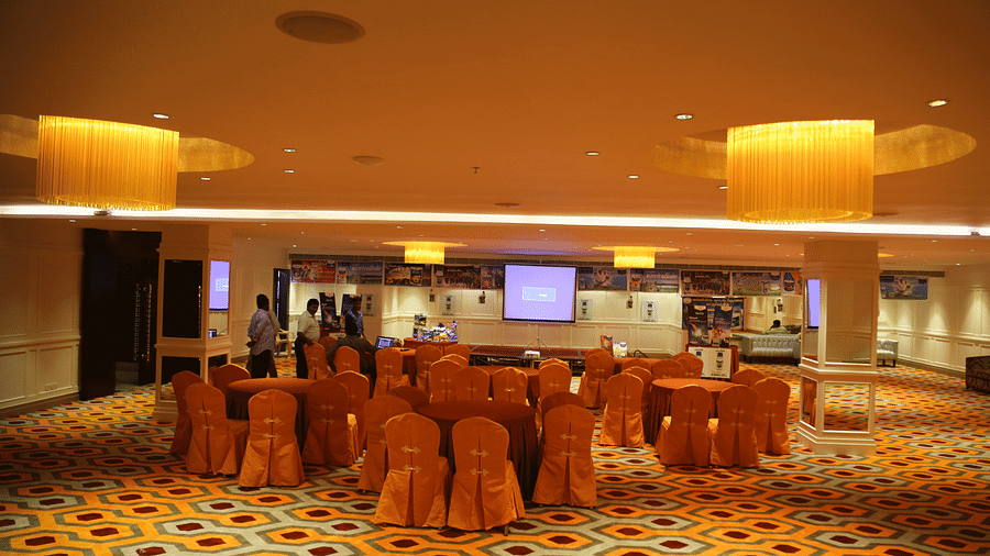 A warmly lit banquet hall with orange chairs arranged around tables - TGI Grand Fortuna, Hosur
