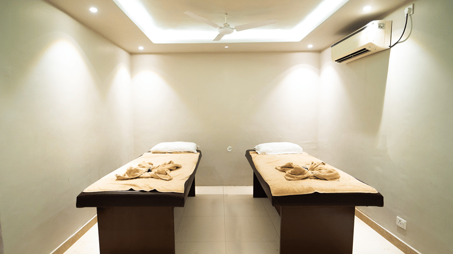 A spacious double massage room equipped with 2 treatment beds, recessed ceiling lights, and air conditioning - Wood Castle Spa & Resort, Jim Corbett