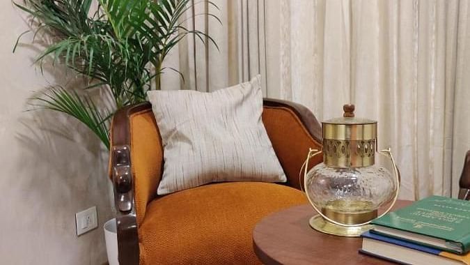 A chair and small table with books are in Luxury King Room at Nalapad Hotel Bangalore International.