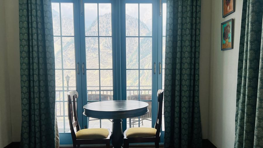 A two-seater round table near a large window  | Faraway Cottages, Auli