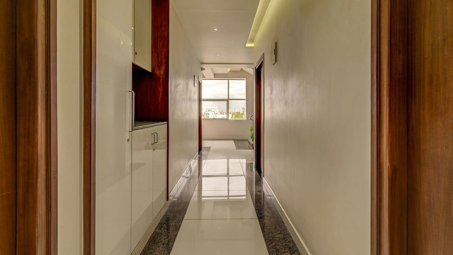 A long corridor at Harigovinda's JNStay, with doors on both sides and a window at the far end