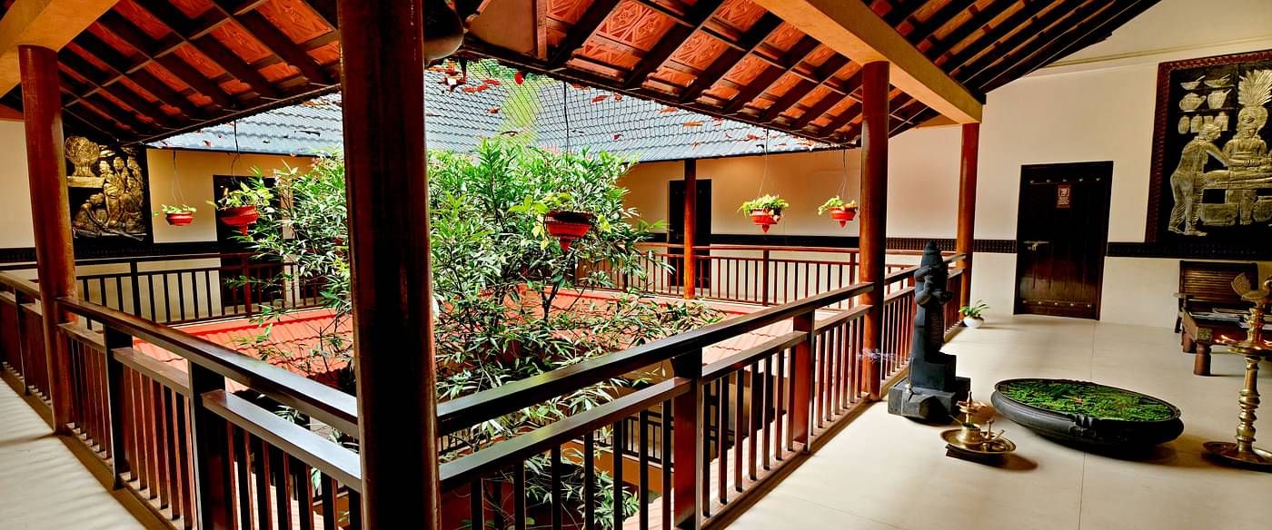 Outdoor corridor with wooden railings and greenery view at Vythiri Resort, Wayanad