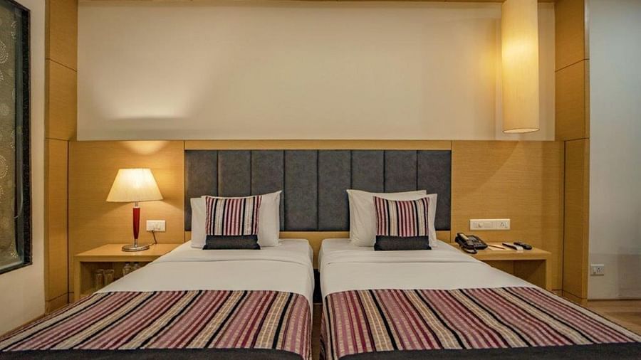 Twin beds with headboard lighting and warm decor in a Golden Tulip guest room.