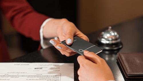 Receptionist handing a key card to a guest at a hotel front desk