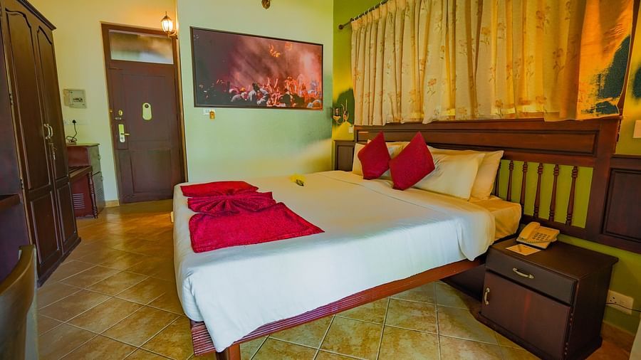Spacious room featuring a large bed, wooden storage units, and photo frames hung on the walls
