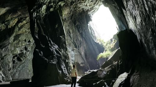 image of a man standing inside a cave with plenty of natural sun light falling inside it