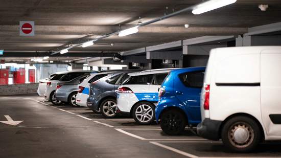Covered hotel parking area with cars and a van parked in designated spaces.