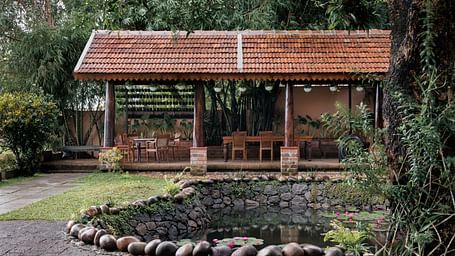 A facade image showcasing the pond at BluSalzz Villas - Muhamma Resort, Alleppey and the outdoor seating area of the restaurant
