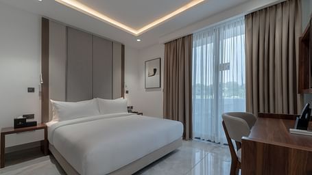 Spacious Standard Room with king size bed, soft lighting, wooden desk, large window, and cozy ambience. - The Pelican Hotel, Accra