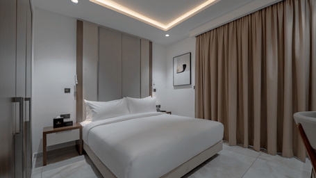 A well-lit Standard Room with a king size bed next to curtains. - The Pelican Hotel, Accra