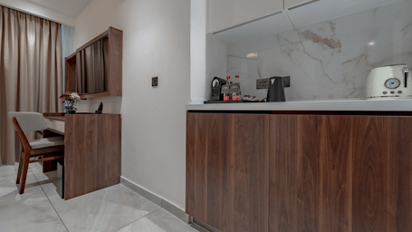 One of the Standard Rooms in Accra with wooden desk with a kettle and toaster under and elegant lighting at The Pelican Hotel