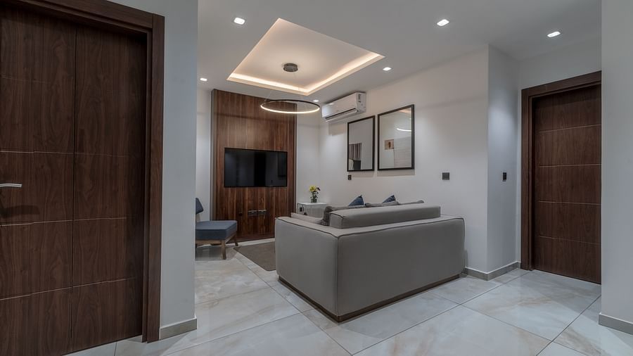 A well-lit, modern Executive Suite featuring a seating area and a closed wooden door.  - The Pelican Hotel, Accra
