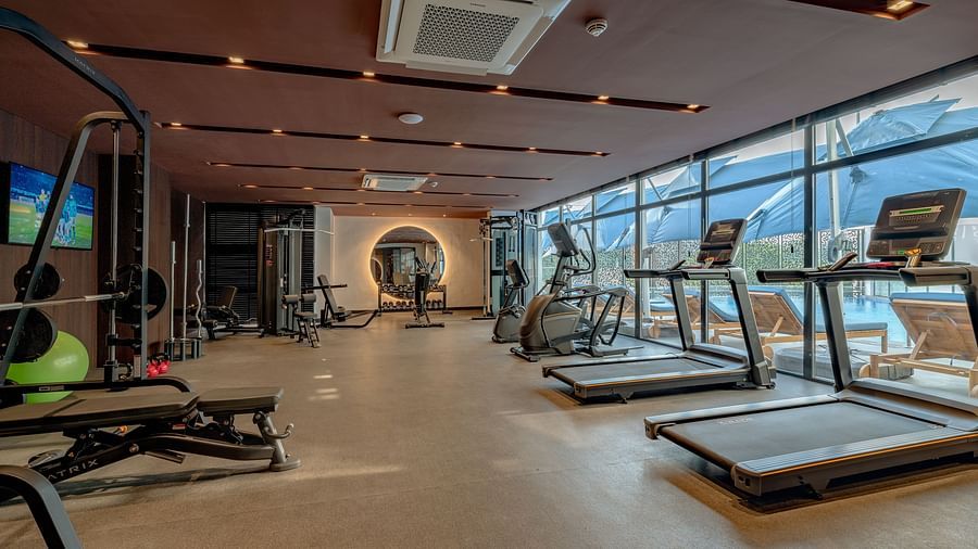 Bright, spacious gym with treadmills and weight machines lining the window wall. - The Pelican Hotel, Accra
