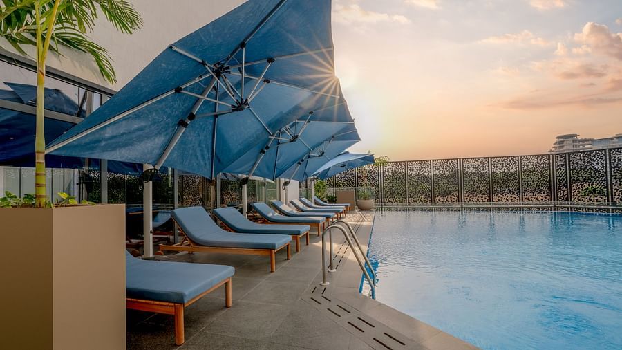 A pristine swimming pool glistens under a warm sunset sky, inviting a refreshing dip. - The Pelican Hotel, Accra