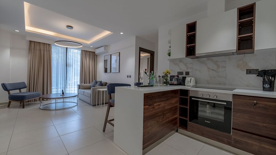 Modern kitchen in a Premier Suite with stainless steel appliances and wood cabinetry. - The Pelican Hotel, Accra