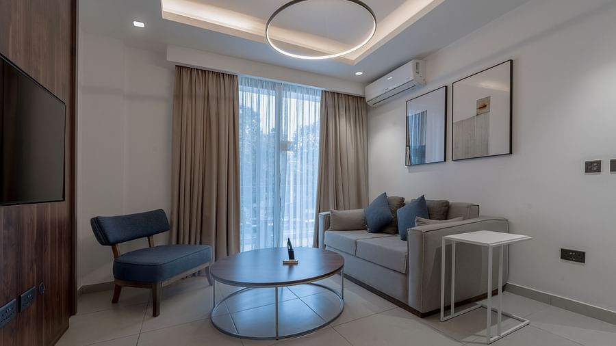 A modern living room in a Premier Suite with stylish furniture, large windows, and elegant decor. - The Pelican Hotel, Accra