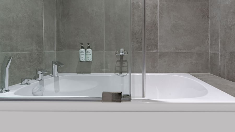 Modern Junior Suite with a bathtub, and a glass shower door. - The Pelican Hotel, Accra