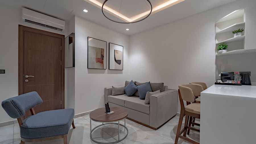 Modern and bright living room of a Junior Suite with sofa, table, and kitchenette. - The Pelican Hotel, Accra