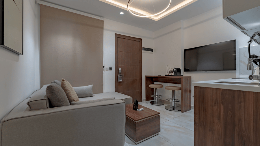 Modern, well-equipped kitchen in one of the Deluxe Rooms in Accra with wooden cabinetry and stainless steel appliances at The Pelican Hotel