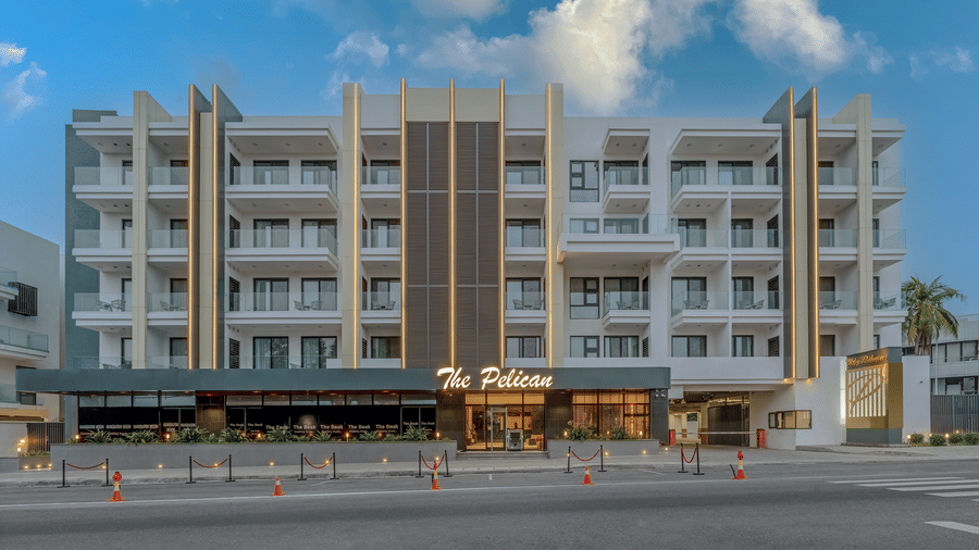 Facade of The Pelican Hotel, Accra, with palm trees in front and a clear blue sky in the background