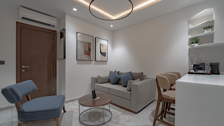 Modern and bright living room of one of the Junior Suites in Accra with a sofa and a table, and kitchenette on one side at The Pelican Hotel