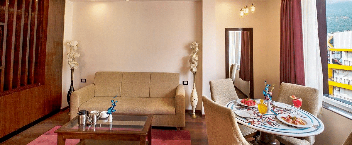 Front view shot of the living area featuring a couch along with a coffee table and a dining table besides it in the Suite at Regenta Inn DLS.