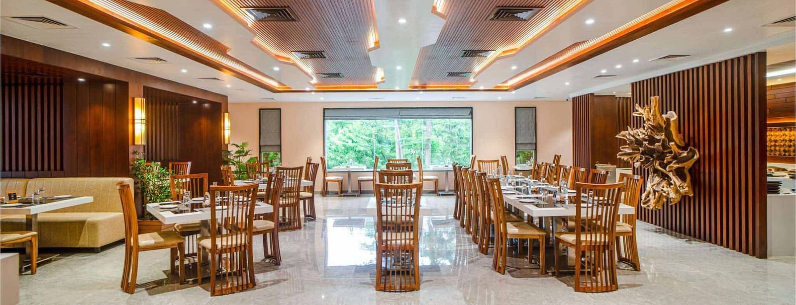 The well-lit dining area at Mansha Palace in Port Blair features neatly set tables and comfortable wooden chairs.
