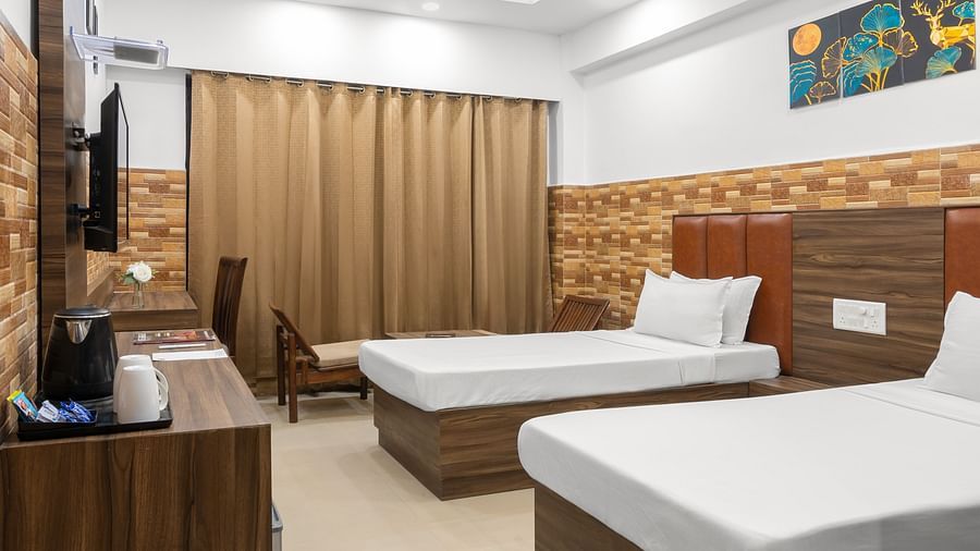 A hotel room with two single beds, a TV stand with a wall mount TV, a wall painting, a desk, and closed curtains.- Clarks Inn Express, Near Jammu Bari Brahmana Railway Station
