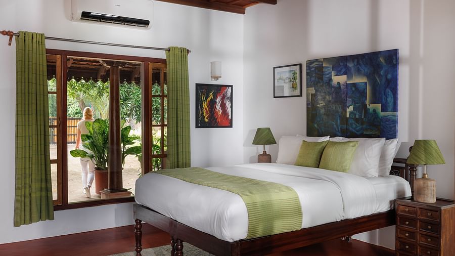 A room with a bed, wooden decorative items, and a glass window overlooking the view - BluSalzz Villas - Muhamma Resort, Alleppey