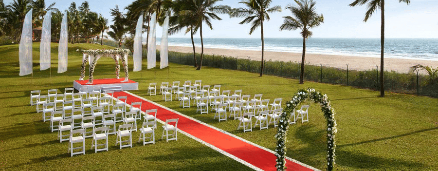 seating arrangements for a Wedding with an arch and red carpet leading to stage - Caravela Beach Resort Goa