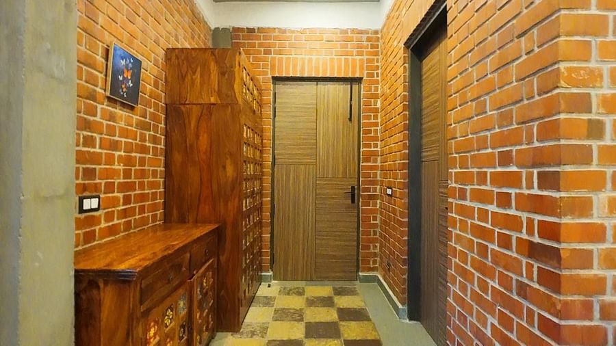 Narrow corridor with checked flooring and brick walls at Tisya Farms, Gurgaon.