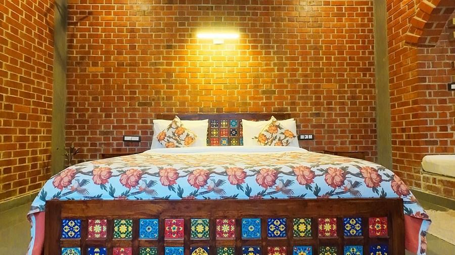 Room with brick walls and a vibrant quilted double bed at Tisya Farms, Gurgaon.
