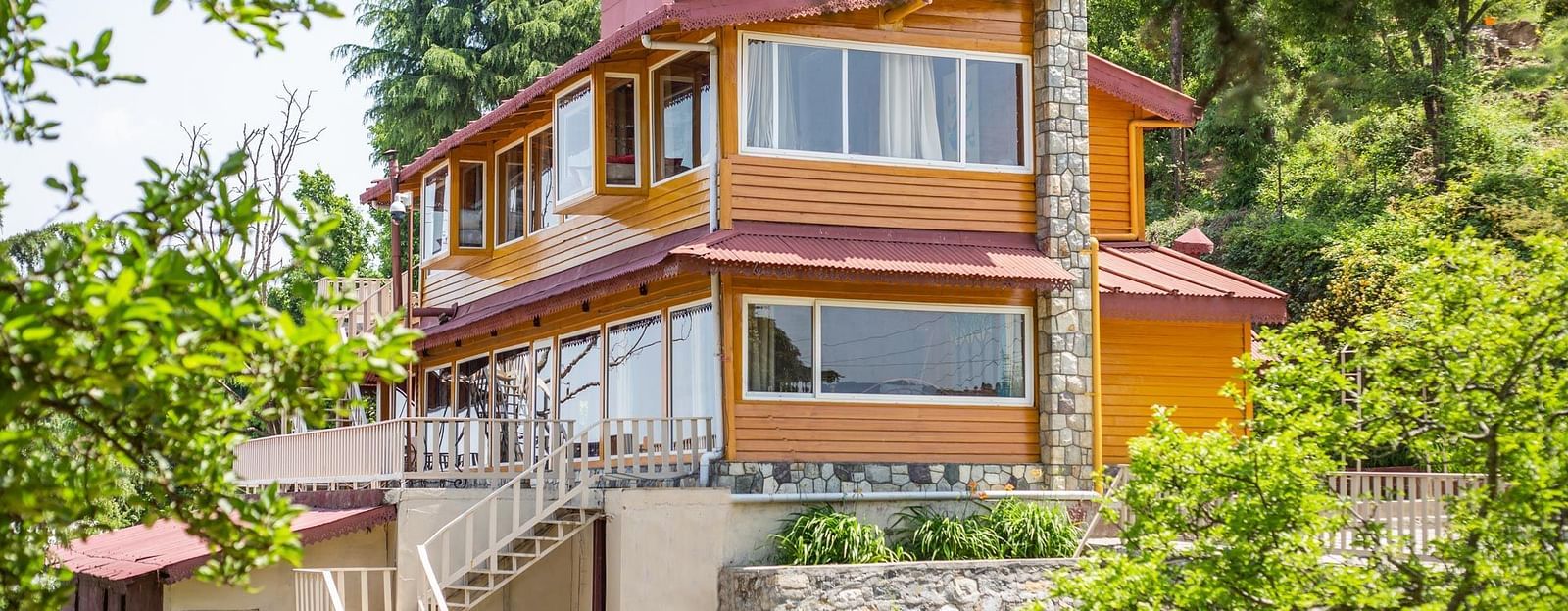 An image of a cottage with stairs and balconies at each floor surrounded by trees everywhere -  Avalon Cottages, Kanatal