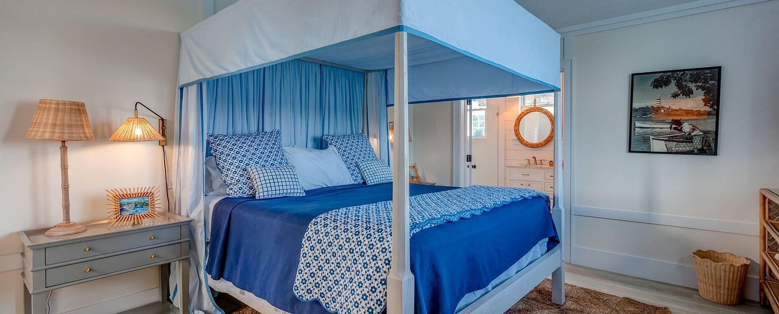 Bedroom with a blue canopy bed, wooden nightstand, and soft lighting | Abaco Inn
