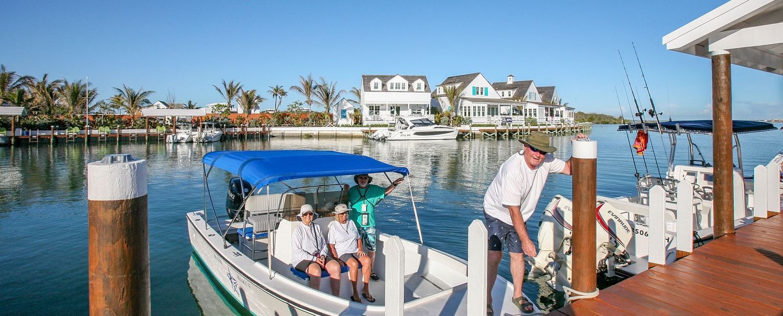 Docked boat by the boardwalk with buildings in the background | Abaco Inn